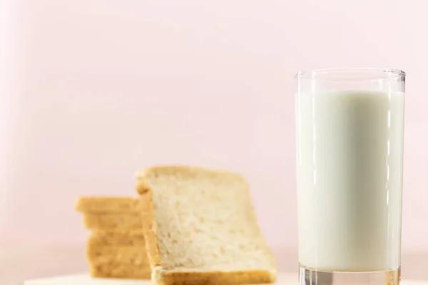 ピンクの背景に新鮮な健康的なミルクとパンを閉じます — ストック写真