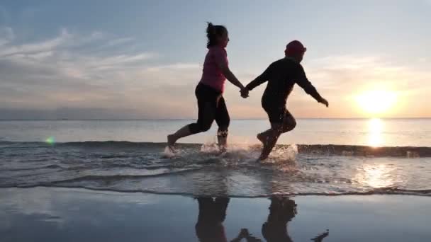 Happy Asian Family On Summer Vacation mother and son holding hands and running together on the beach In the evening sunset. Holiday, Happy family time and Travel concept. Slow motion