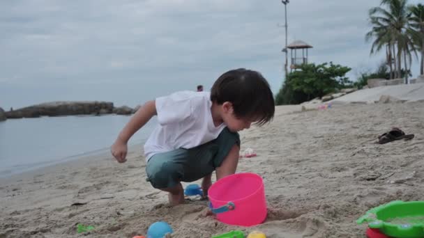 快乐的亚洲男孩在沙滩上玩耍 早上的时候 假期和旅行的概念 慢动作 — 图库视频影像