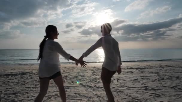 リアビューハッピーアジアの若いカップルは手を取り合い ビーチで一緒に走るのが大好きです 海の背景日没 休日や旅行のコンセプト スローモーション — ストック動画