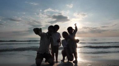 Mutlu Asyalı Aile Yaz Tatili Baba sahilde akıllı telefonuyla aile fotoğrafı çekiyor. Gevşe Tatil ve Seyahat konsepti. Yavaş çekim