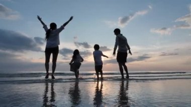 Mutlu Asyalı Aile Yaz Tatili Baba, Anne, Oğul ve Kız Sahilde Su Denizi Oynayacağız. Denizde günbatımı. Gevşe Tatil ve Seyahat konsepti. Yavaş çekim