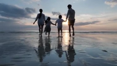 Mutlu Asyalı Aile Yaz Tatili Baba, anne, oğul ve kız el ele tutuşup birlikte sahile doğru koşuyorlar. Denizde günbatımı. Gevşe Tatil ve Seyahat konsepti. Yavaş çekim
