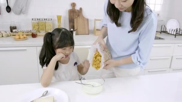 幸せなアジアの家族お母さんと女の子は自宅でキッチンで朝食を食べています 家庭料理のコンセプト — ストック動画