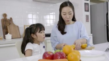 Mutlu Asyalı aile, küçük kız afiyet olsun. Annem de evde sebze ve meyve hazırlıyor. Sağlıklı gıda konsepti