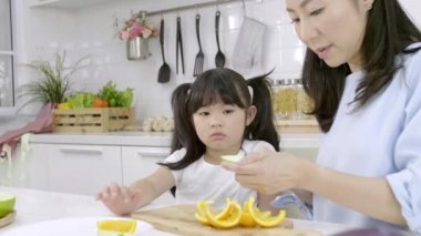 Mutlu Asyalı aile, küçük kız afiyet olsun. Annem de evde sebze ve meyve hazırlıyor. Sağlıklı gıda konsepti