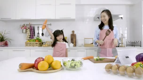 幸せなアジアの家族一緒に好きな歌にダンスを移動自宅のキッチンルームで陽気な母親と小さな娘 余暇とライフスタイルのコンセプト — ストック動画