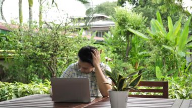 Asyalı adam evde bilgisayar başında çalışırken yorgun ve baş ağrısını vurguladı. İş sorunları, ekonomik sorunlar, iş başarısızlığı. Yavaş Hareket