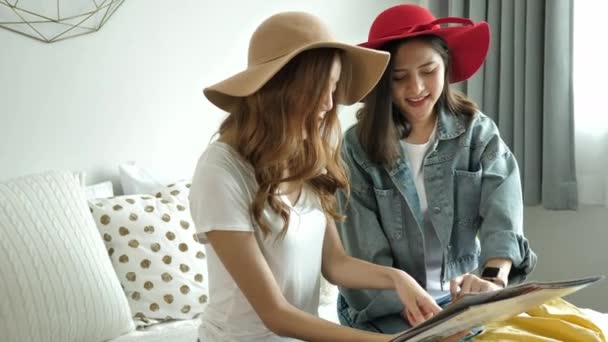 ハッピー二人のアジアの若い女性は旅行休暇のために家でベッドの上の地図で夏の旅行を計画笑っています — ストック動画
