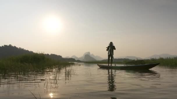 漁師のシルエットは湖のボートで日没時に漁網を準備します コンセプトフィッシャーマンズライフスタイル タイのロッブリ — ストック動画