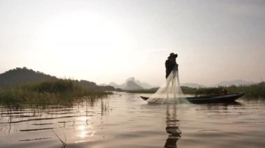 Balıkçılar, gün batımında gölde teknelerle balık ağını attıktan sonra sudan yükselen ağları çekiyorlar. Kavramsal Balıkçı yaşam tarzı. Lopburi, Tayland. Yavaş Hareket