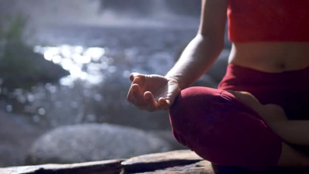 莲花在瀑布边的亚洲女子练习或做瑜伽 在冥想时摆出姿势 美丽的风景 自然背景 — 图库视频影像