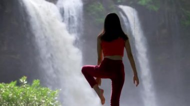 Şelalede yoga yapan Asyalı bir kadın. Güzel manzara, doğal arka plan, Tayland. Kadın profesyonel yoga.