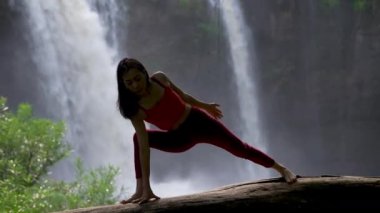 Şelalede yoga yapan Asyalı bir kadın. Güzel manzara, doğal arka plan, Tayland. Kadın profesyonel yoga.