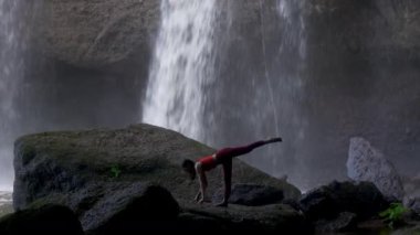 Şelalede yoga yapan Asyalı bir kadın. Güzel manzara, doğal arka plan, Tayland. Kadın profesyonel yoga.