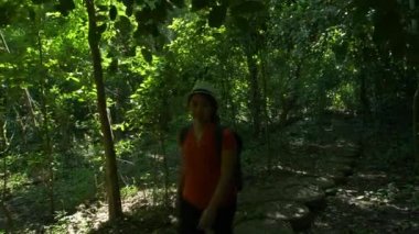 Sırt çantalı Asyalı kadın sabah ormanda ve güneş ışığında yürüyor. Orman gezisinde yürüyüş yapan yürüyüşçüler Asya Tayland
