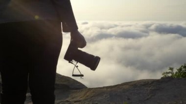 Kadın fotoğrafçı Hand 'in sabah DSR kamerasını tutuşu ve güneşin doğuşu sırasında dağın zirvesinde sis, deniz sisi doğa arka planı. Turizm, Seyahat, Profesyonel Fotoğrafçı