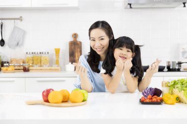 Mutfakta Mutlu Asyalı aile portresi var. Keyfiniz yerinde Anne ve küçük kız size gülümsüyor