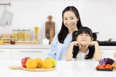 Mutfakta Mutlu Asyalı aile portresi var. Keyfiniz yerinde Anne ve küçük kız size gülümsüyor