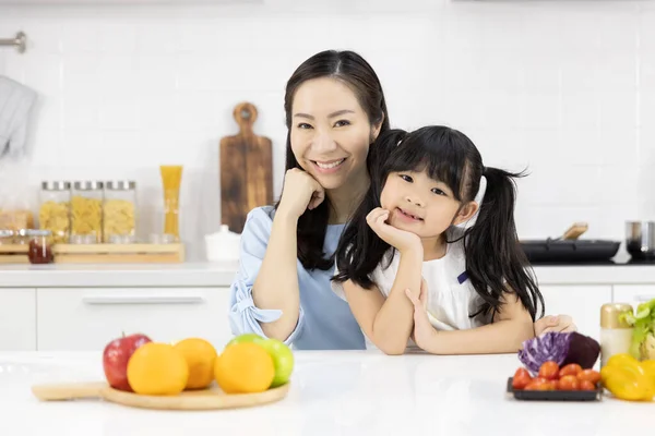 Portrait of Happy Asian family in the kitchen. Good mood Mother and Little girl Smiling at you