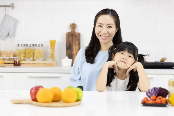 Portrait of Happy Asian family in the kitchen. Good mood Mother and Little girl Smiling at you