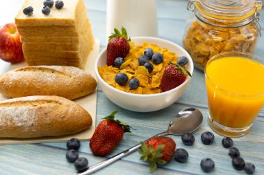 Sağlıklı kahvaltı. ekmek, portakal suyu, çilek, yabanmersini, süt ve tahıl gevreği ahşap masada. Sağlıklı yemek.
