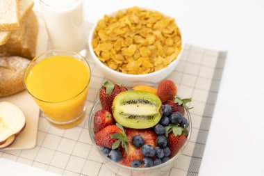 Sağlıklı kahvaltı. ekmek, portakal suyu, çilek, yabanmersini, kivi, süt ve mısır gevreği hasırda. Sağlıklı yemek.
