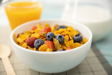 Sağlıklı kahvaltı. Portakal suyu, meyve, çilek, yaban mersini ve tahıl gevreği hasırda ve ahşap masada. Arka plan Sağlıklı yiyecekler.