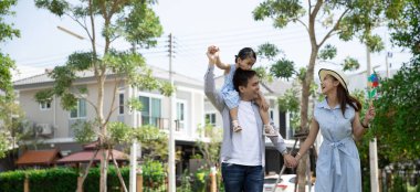 Mutlu Asyalı aile. Babası, kızına, güneş ışığının arka planında ve evinde bir parkta sırt sırta vermiş. Kopya alanı olan aile tatili kavramı