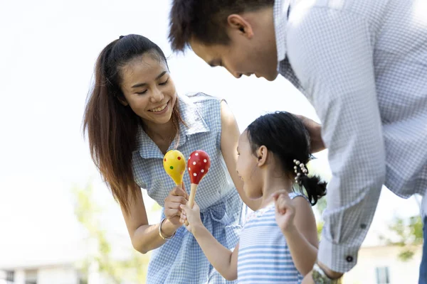 Happy Asian family. Father, mother and daughter in a park at natural sunlight background. Family vacation concept.