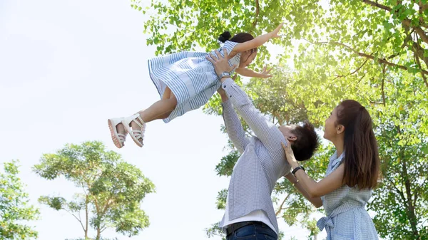 幸せなアジアの家族 父は自然光の背景と家の公園で空の娘を投げ出します コピースペースと家族の休暇のコンセプト ロイヤリティフリーのストック写真