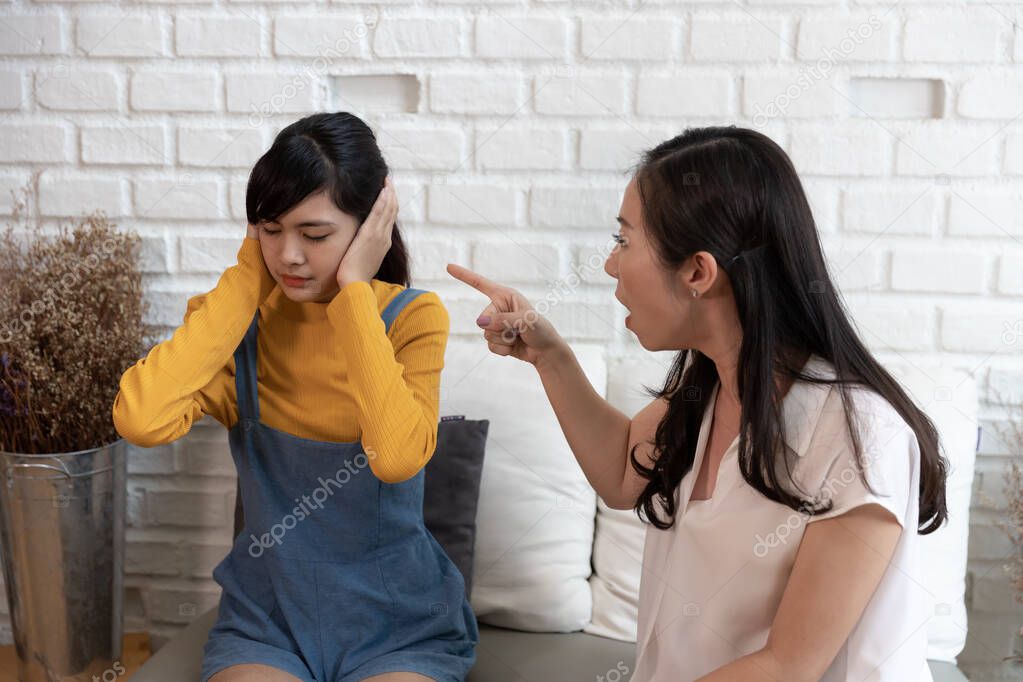 Asian family Teenage daughte closed his ears with his hands while her mother yells at her at home. Family crisis, conflict and relationships problems concept