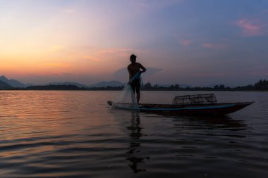 Asyalı balıkçı, alacakaranlıkta balıkçı ağıyla doğa nehrinde balık tutuyor. Kavramsal Balıkçının kırsal yaşam tarzı. Lopburi, Tayland, Asya