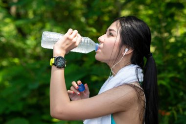 Koşudan sonra biberondan su içen güzel Asyalı kadınlar. Sabahleyin bahçede. Sağlıklı içme suyu ve egzersiz kavramı
