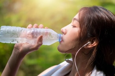 Koşudan sonra biberondan su içen güzel Asyalı kadınlar. Sabahleyin bahçede. Sağlıklı içme suyu ve egzersiz kavramı