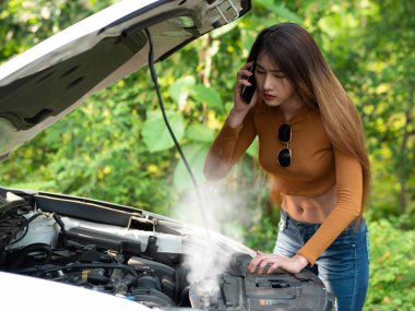 Young asian women tourist near a broken car on the country road is calling on smart phone Asking for Help. Smoke out the radiator a car, Over Heat clipart