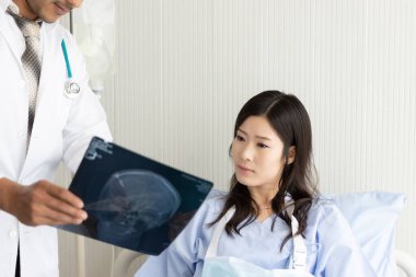 Röntgen filmli doktor ve hastanede yatan Asyalı kadın hasta.