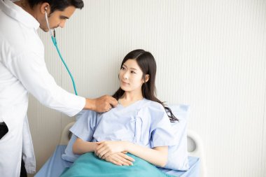 Doktor steteskopla hastanede yatan Asyalı kadın hastaları kontrol ediyor. Sağlık sorunları, hastalık konsepti