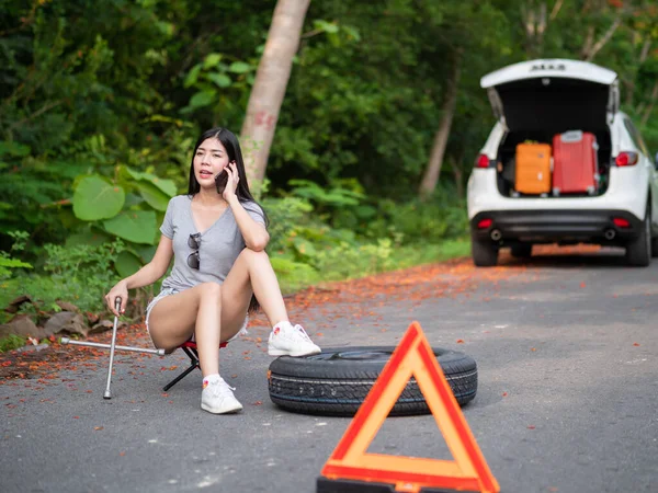 Young asian women tourist near a broken car on the country road is calling on smart phone Asking for Help.