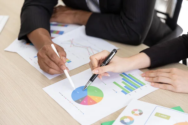 Close up Hand of business people man and asian woman in black suit talking  planning business strategy. They pointing paperwork Marketing plan researching. Business teamwork, brainstorming concept