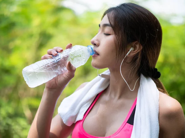 ジョギングの後 ボトルから水を飲む美しいアジアの女の子のクローズアップ 庭での朝 健康運動の概念 ストックフォト