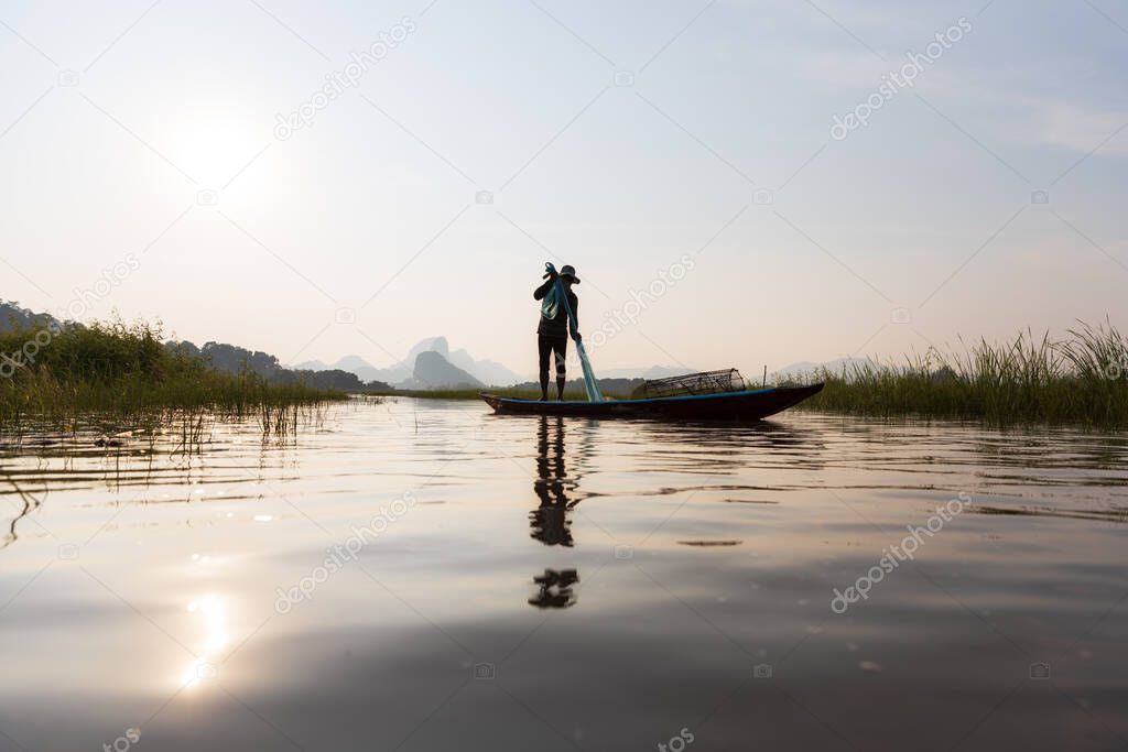 Asian fishermen prepare fishing net during sunset on boats at the lake.  Concept Fisherman's Lifestyle in countryside. Lopburi, Thailand, Asia