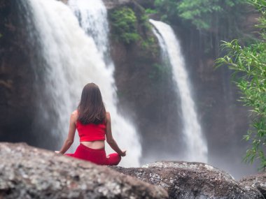 Şelalede yoga yapan Asyalı bir kadın. Güzel manzara, doğal arka plan, Tayland.