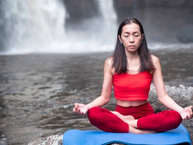 Şelalede yoga yapan Asyalı bir kadın. Güzel manzara, doğal arka plan, Tayland.