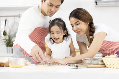Mutlu Asyalı aile babası, anne ve kız hamuru hazırlıyor, evde mutfakta kurabiye pişiriyor. Aile yemekleri kavramı.