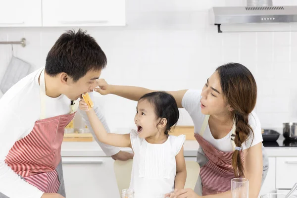 幸せなアジアの家族は料理を作る お父さん お母さん 娘さんが自宅のキッチンで朝食を食べています パンにジャム 健康食品のコンセプト ストックフォト