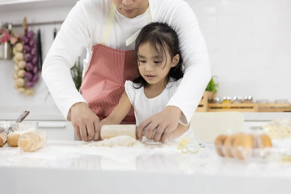 幸せなアジアの家族の父と娘は 自宅で台所でパン屋を作るためにピンのスリリングな小麦粉を転がしています 家庭料理のコンセプト ストック写真