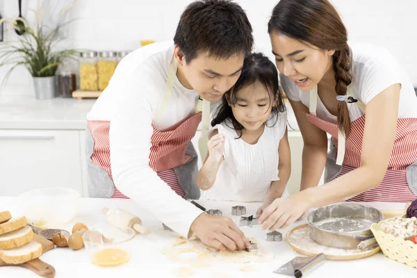 幸せなアジアの家族の父 母と娘は 家庭で台所でクッキーを焼く 生地を準備している 家庭料理のコンセプト ストック画像