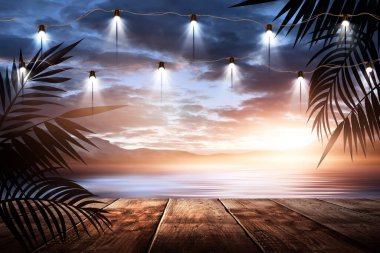İskelede bir gece feneri, gün batımlı bir deniz manzarasının arka planına karşı. Palmiye dalları, siluetler, güneş ışığı. Tahta masa. Gece görüşü, açık deniz manzarası.
