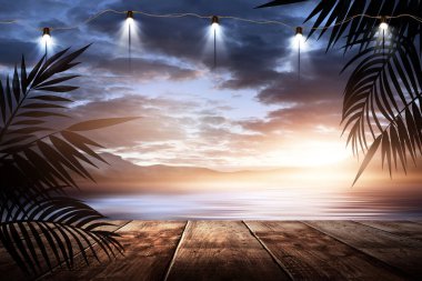 İskelede bir gece feneri, gün batımlı bir deniz manzarasının arka planına karşı. Palmiye dalları, siluetler, güneş ışığı. Tahta masa. Gece görüşü, açık deniz manzarası.